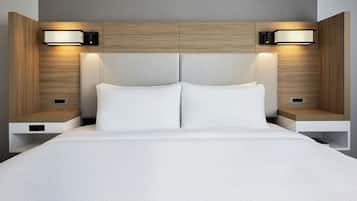 Une chambre d’hôtel moderne avec un grand lit, deux tables de chevet et des lampes fixées au mur.