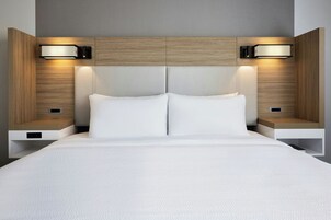 Una habitación de hotel moderna con una cama grande, dos mesitas de noche e iluminación en la pared.