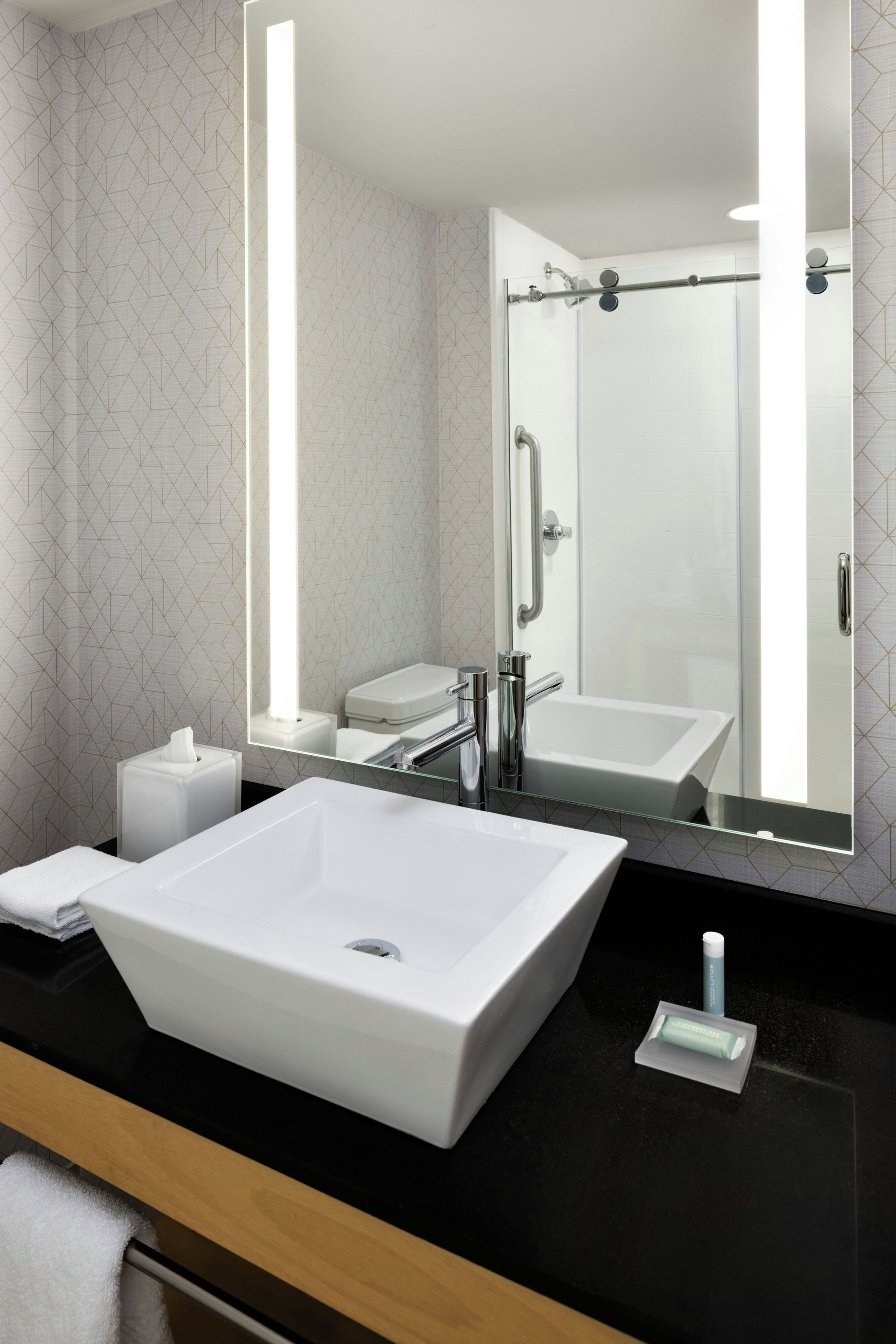 Un baño moderno con un lavabo blanco grande, un espejo y una ducha.