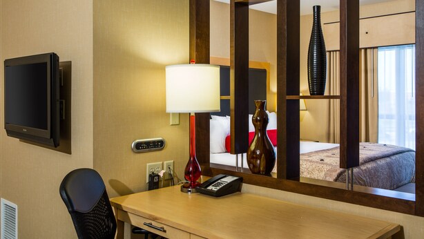 A hotel room with a desk, chair, TV, lamp, phone, and a mirror reflecting the bed and a vase. - SpringHill Suites by Marriott Appleton (Appleton)