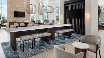 A modern kitchen with a long island, bar stools, and a flat-screen TV mounted on the wall.