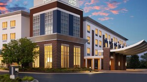 A modern hotel with a prominent signage for Springhill Suites by Marriott, featuring a brick facade, large windows, and a covered entrance.