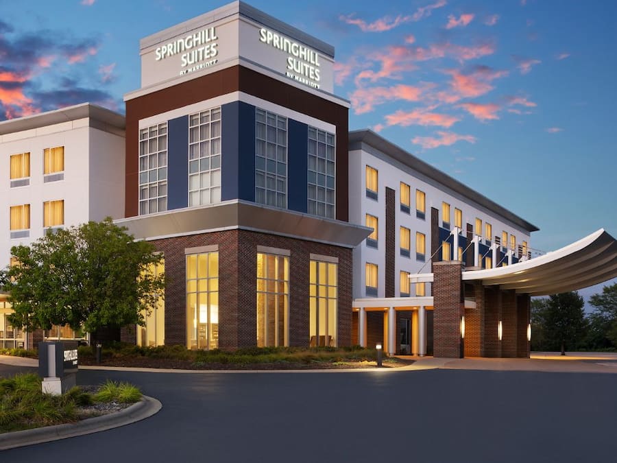 A modern hotel with a prominent signage for Springhill Suites by Marriott, featuring a brick facade, large windows, and a covered entrance.