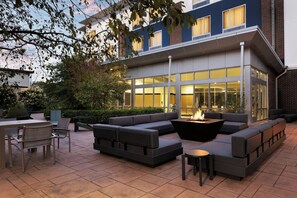 An outdoor seating area with a fire pit, cushioned seating, and a table. - SpringHill Suites by Marriott Appleton (Appleton)