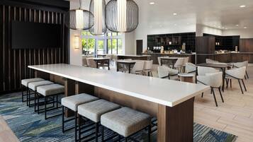 Una cocina moderna con una isla central, asientos tipo barra y un comedor con sillas altas.