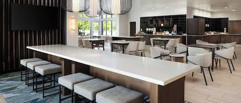 A modern kitchen with a central island, bar seating, and a dining area with high chairs.