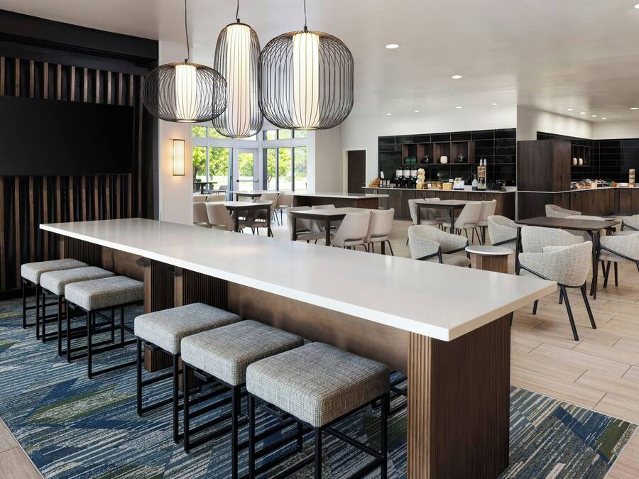 Una cocina moderna con una isla central, asientos tipo barra y un comedor con sillas altas.
