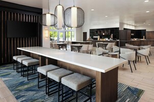 Una cocina moderna con una isla central, asientos tipo barra y un comedor con sillas altas.