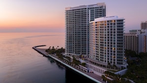 A high-rise hotel with a modern design, featuring multiple balconies and a waterfront view.