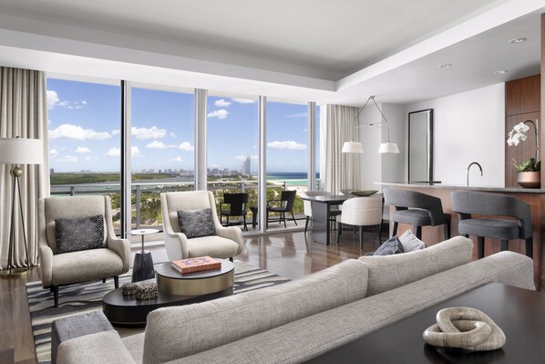 A modern living room with a large window, a sofa, armchairs, and a dining area.