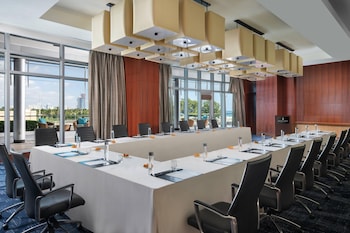 A modern hotel room with a large bed, a desk, a chair, and a small cabinet. at The Ritz-Carlton Bal Harbour, Miami