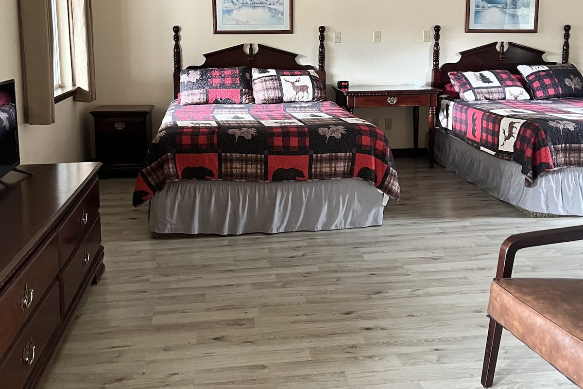 A bedroom with two beds, wooden floors, and a dresser.