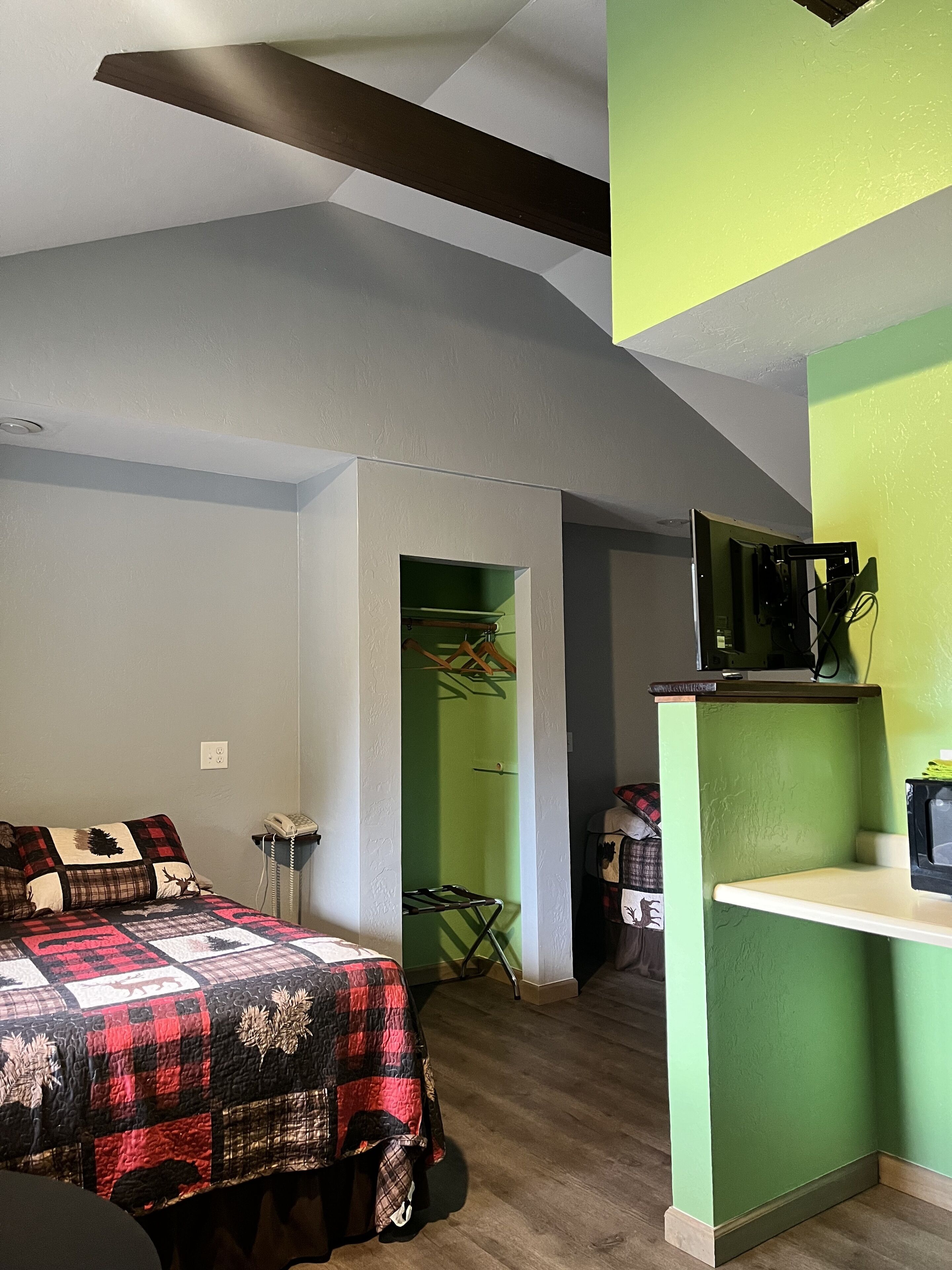 A bedroom with a bed, a desk, and a television.