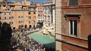 Una piazza affollata con una fontana, edifici storici e vista sul fiume Tevere.