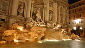 Imponente struttura architettonica con colonne e statue classiche, una fontana centrale e un elemento acquatico circostante.