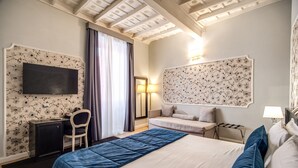 Una camera d'albergo con un letto, una scrivania, una sedia e un televisore fissato al muro.
