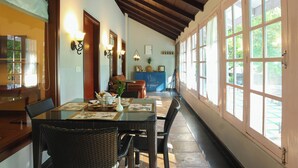 A dining area with a long table, wicker chairs, and a blue cabinet in the background.