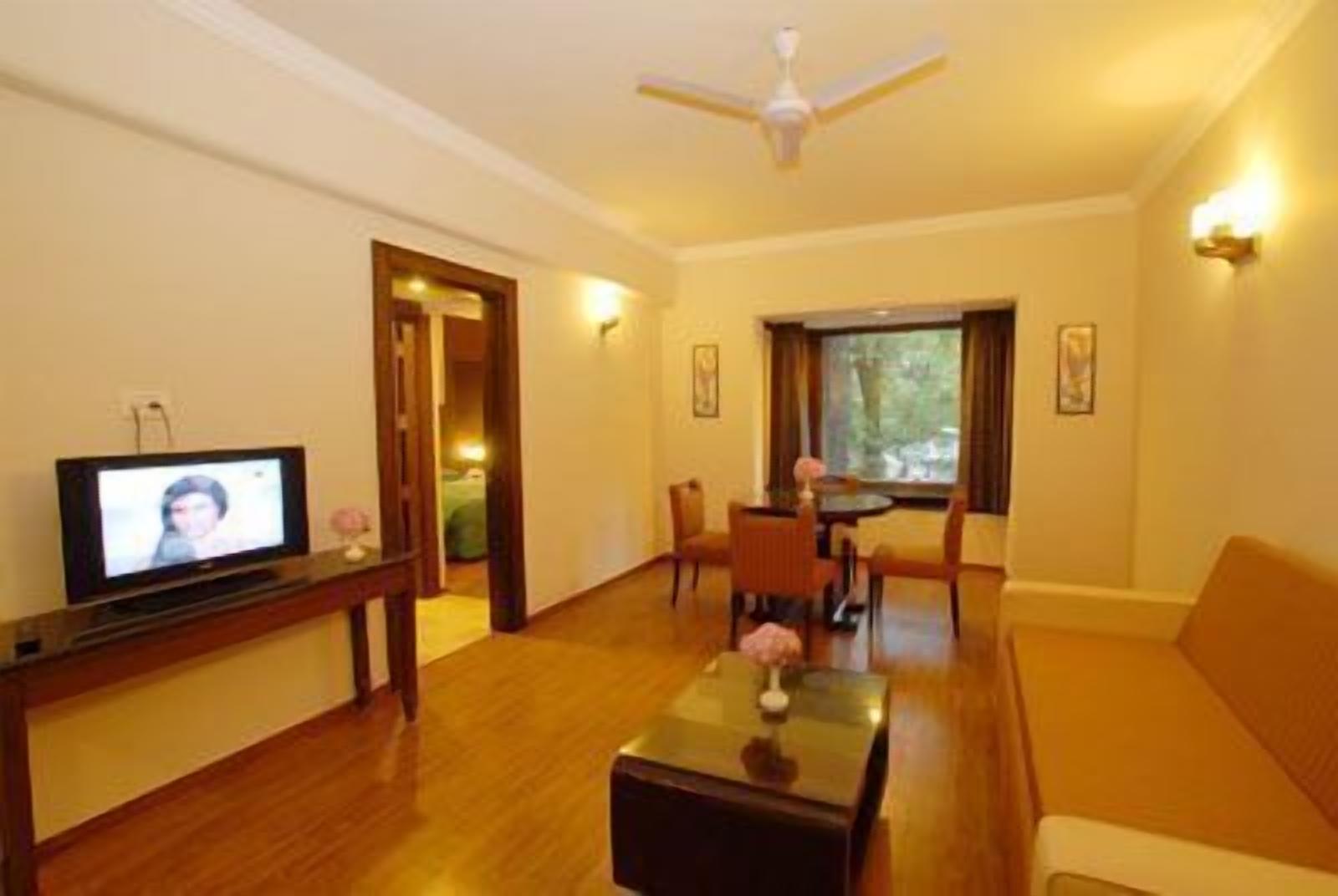 A living room with a television, a dining table with chairs, a sofa, and a ceiling fan.
