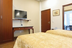 Une chambre d’hôtel avec deux lits, une télévision, un bureau et une armoire.