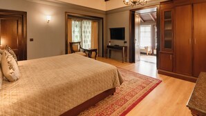 A bedroom with a large bed, wooden wardrobe, and a television on a stand.