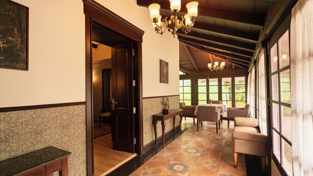 A hallway with a wooden ceiling, a chandelier, and a dining area with chairs and a table.