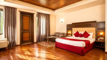 A hotel room with a large bed, a sofa, a small table, and a door.