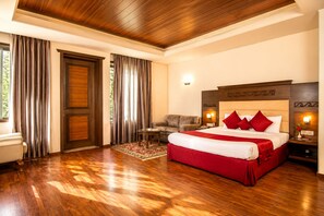 A hotel room with a large bed, a sofa, a small table, and a door. - Vikram Vintage Inn (Nainital)