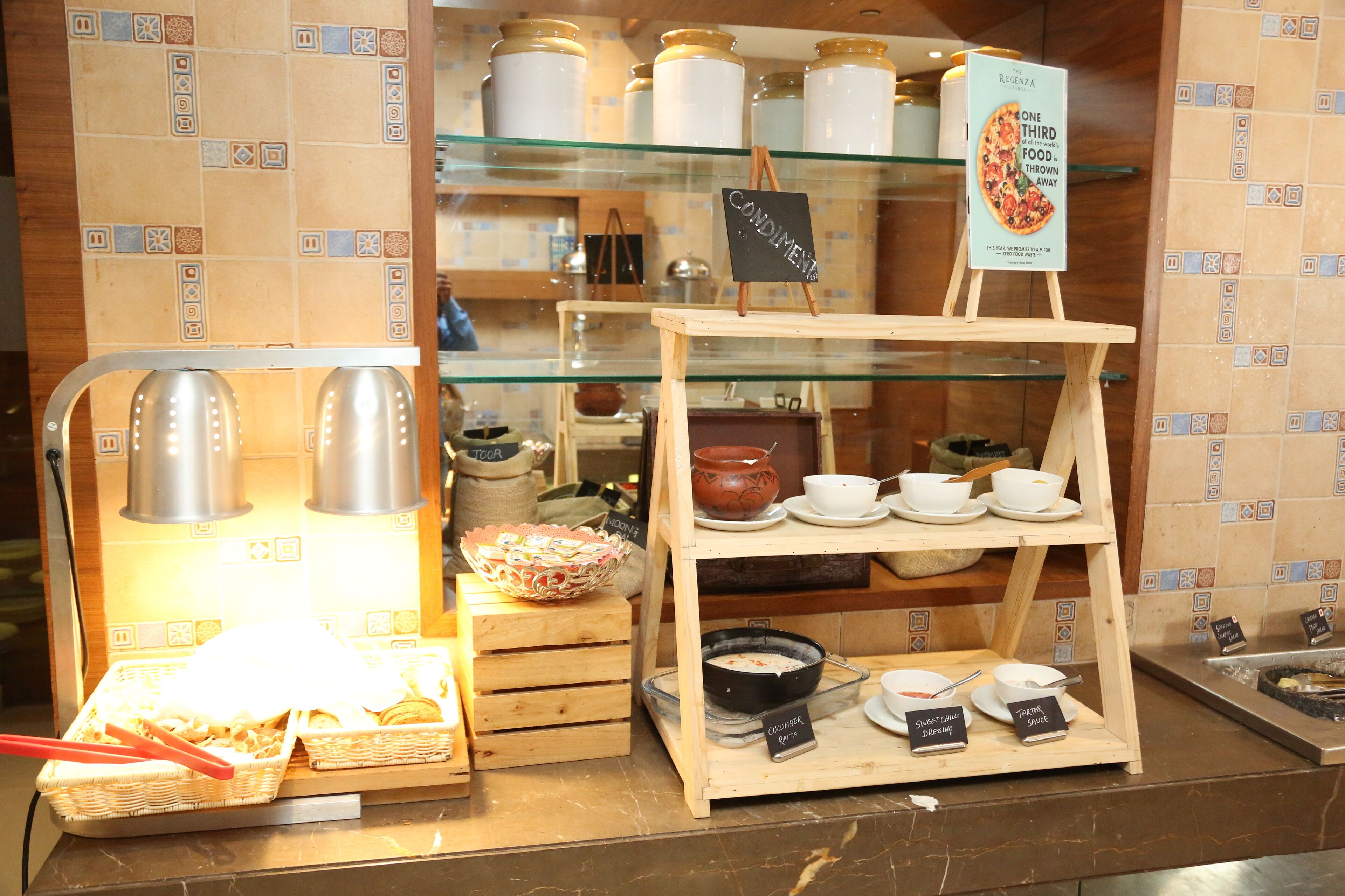 Un área de bufé con diversos alimentos y condimentos exhibidos en estantes y recipientes.