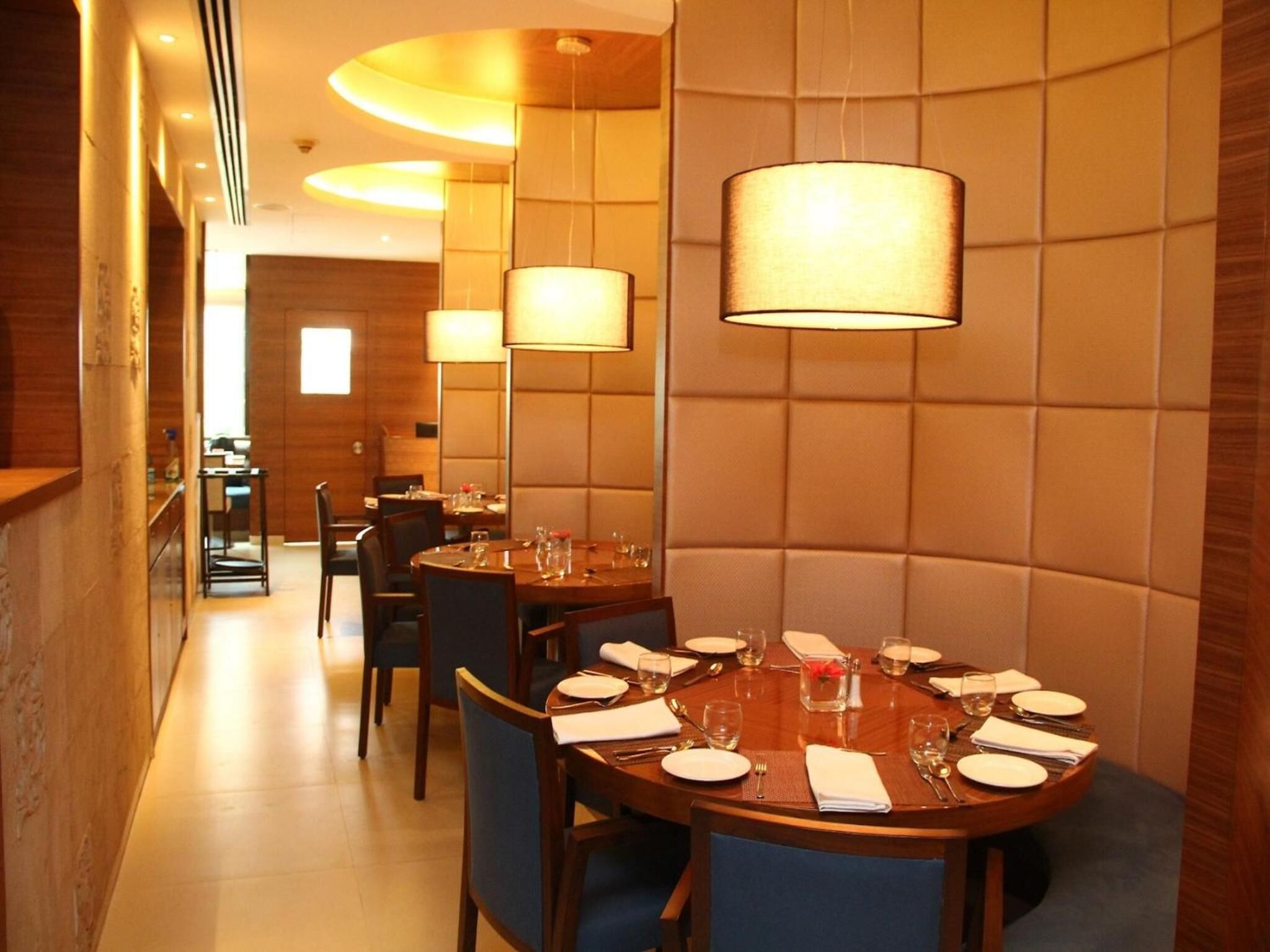 A dining area with round tables, chairs, and pendant lighting.