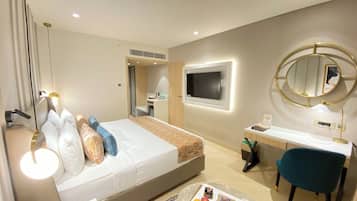 Habitación de hotel con cama, mesita de noche, escritorio, silla y un espejo grande.