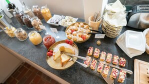 Een buffet met diverse gerechten, waaronder gebak, fruit en sauzen.