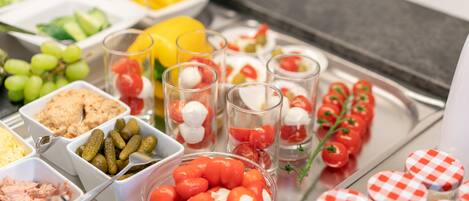 Un bufé con una variedad de alimentos, entre ellos frutas, verduras y salsas.