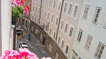 A narrow street with buildings on either side, a motorbike, and a car.