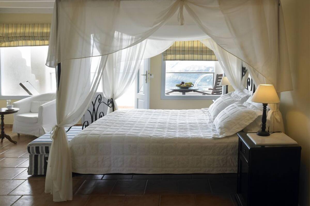 Une chambre à coucher avec un lit à baldaquin, une chaise, une table de chevet et une lampe.