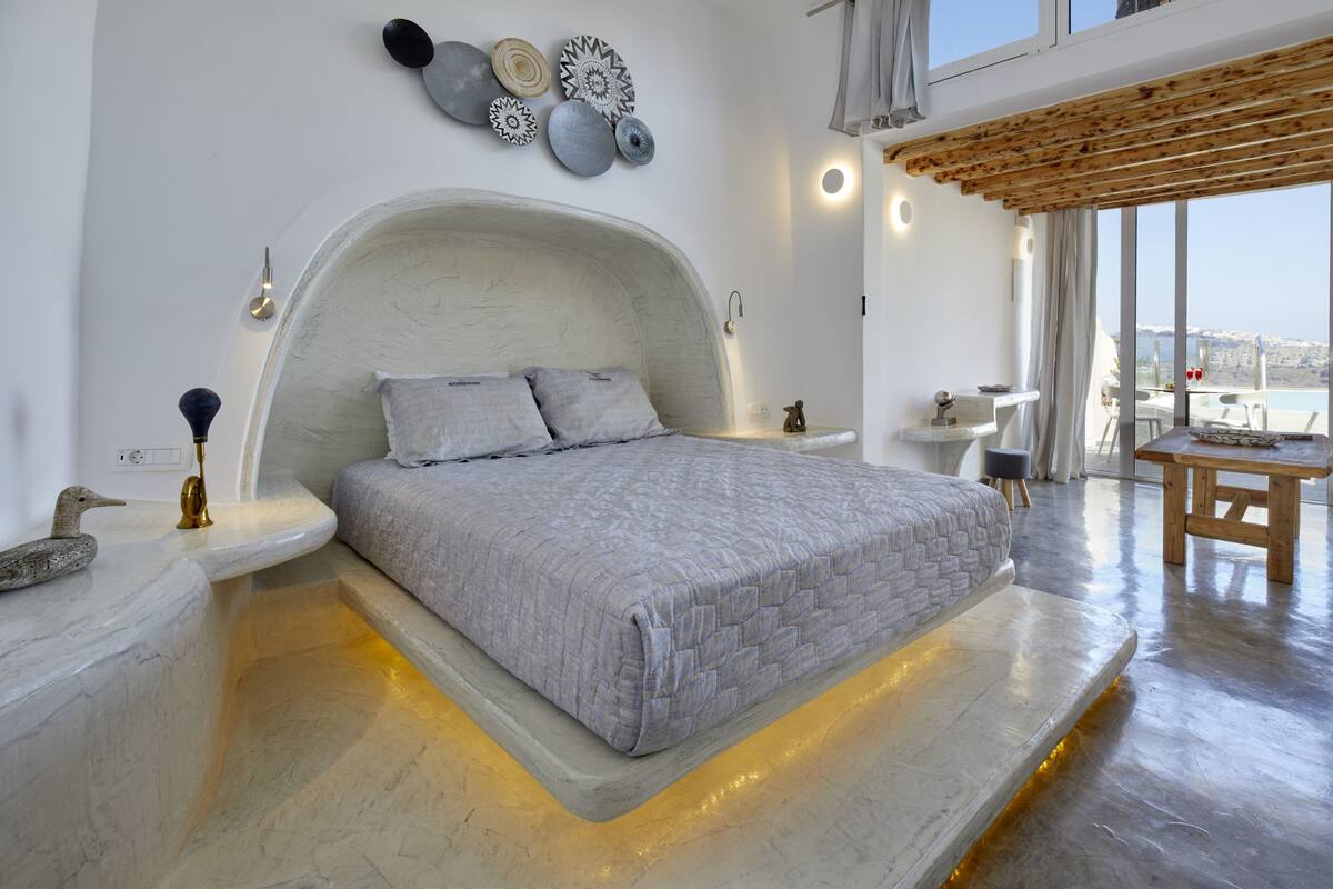 Une chambre moderne avec un grand lit, un plafond en bois et une vue sur la mer.