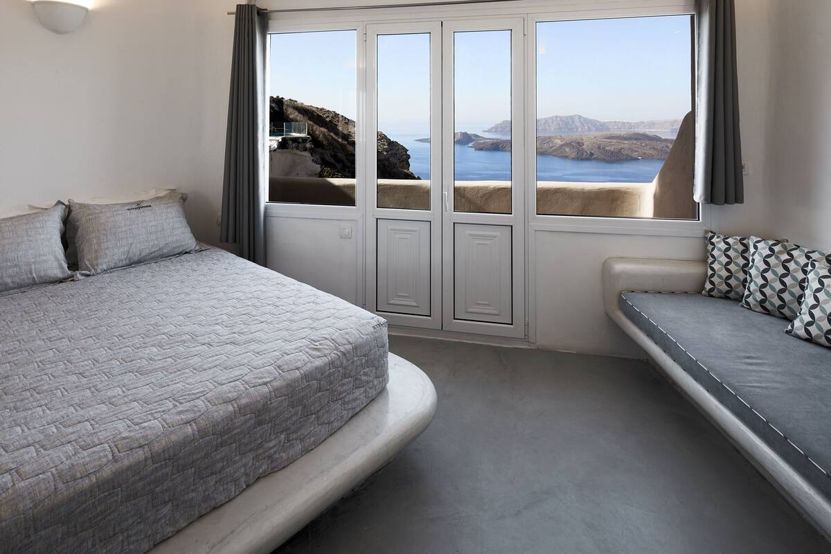 Une chambre avec un lit, un banc et une vue sur la mer.