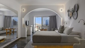 Una habitación de hotel moderna con una cama grande, un comedor y vistas al paisaje.