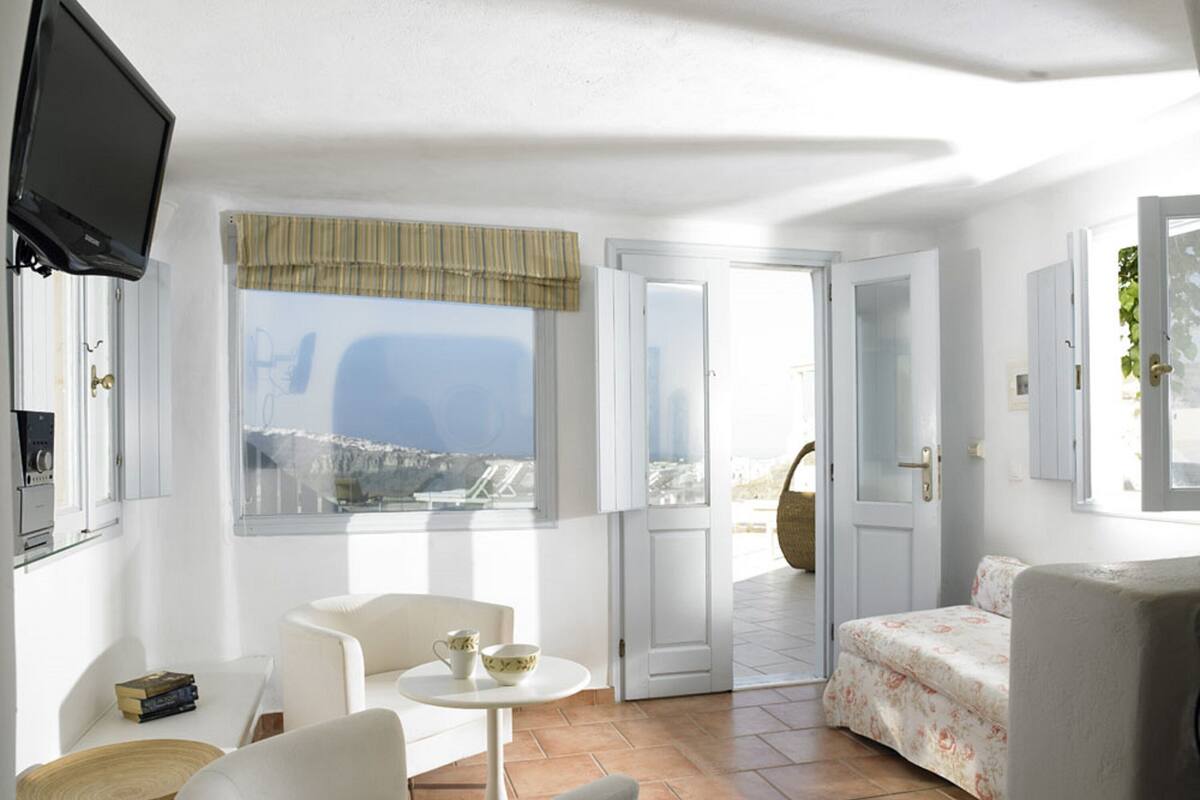 Une pièce avec une télévision, une fenêtre donnant sur un paysage agréable, une porte menant à l’extérieur et un lit.