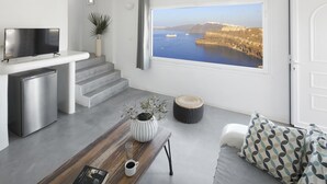 Una sala de estar moderna con un ventanal grande, un televisor de pantalla plana, una mesa de centro con un libro y una taza, y un sofá con cojines estampados.