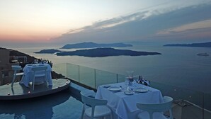 Un comedor con una mesa lista para dos personas, con vista a un cuerpo de agua y islas distantes.