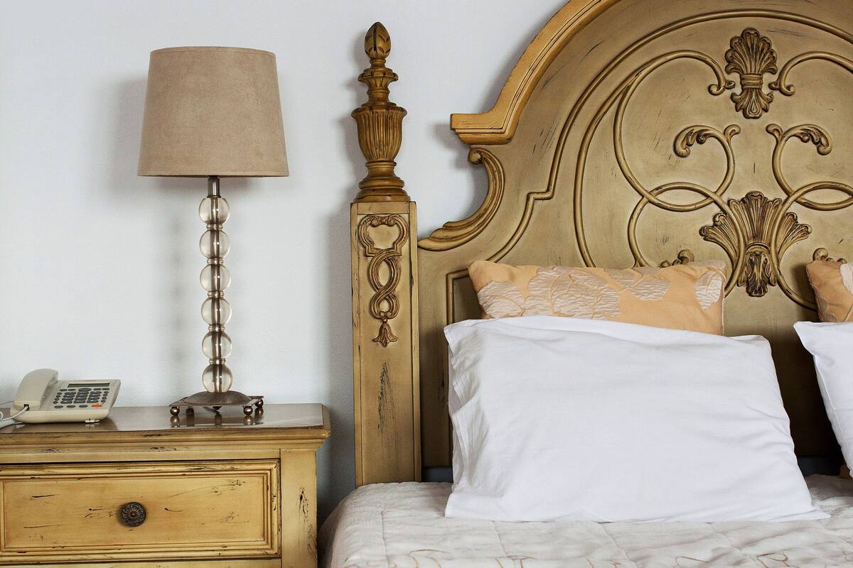 Un lit avec une tête de lit, une table de chevet avec une lampe et un téléphone.