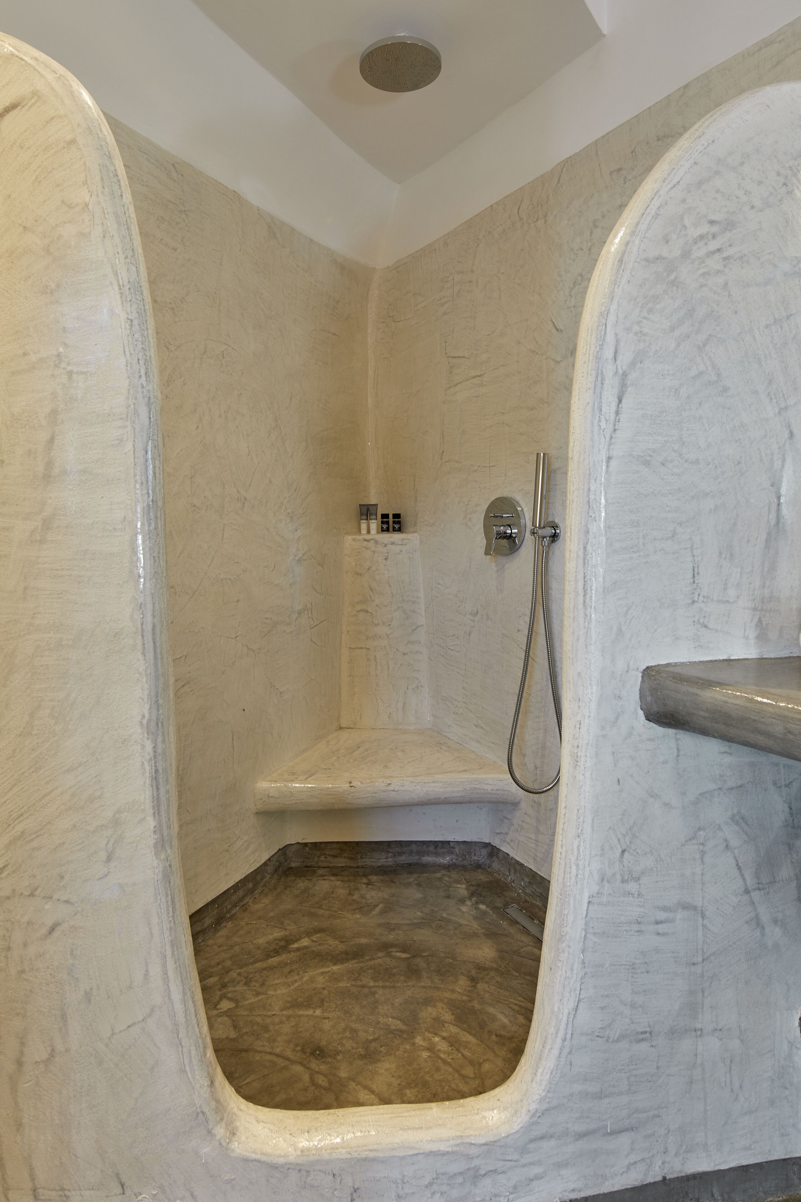 A bathroom with a shower, marble walls, and a showerhead.