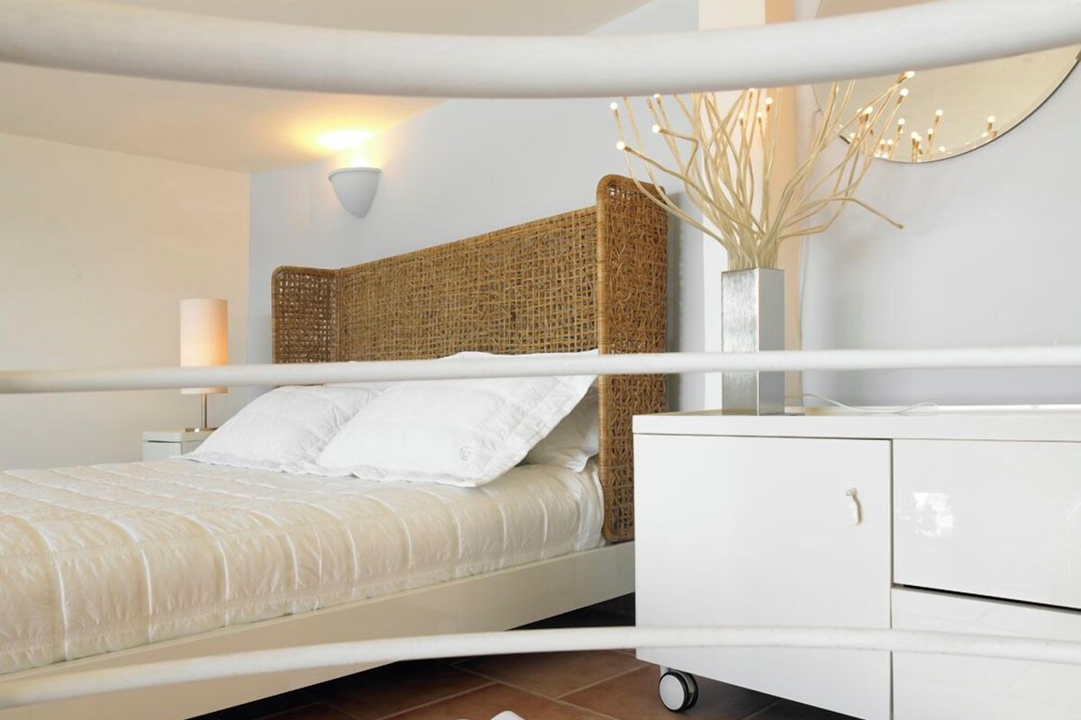 A modern bedroom with a bed, white nightstand, and a white dresser with drawers.
