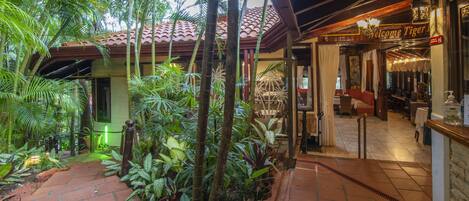 A tropical-themed hotel interior with a brick pathway, lush greenery, and a 'Welcome Tiger' sign.