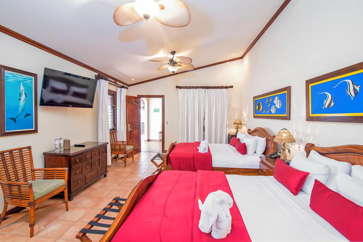 A hotel room with a bed, a chair, a TV, and artwork on the walls.