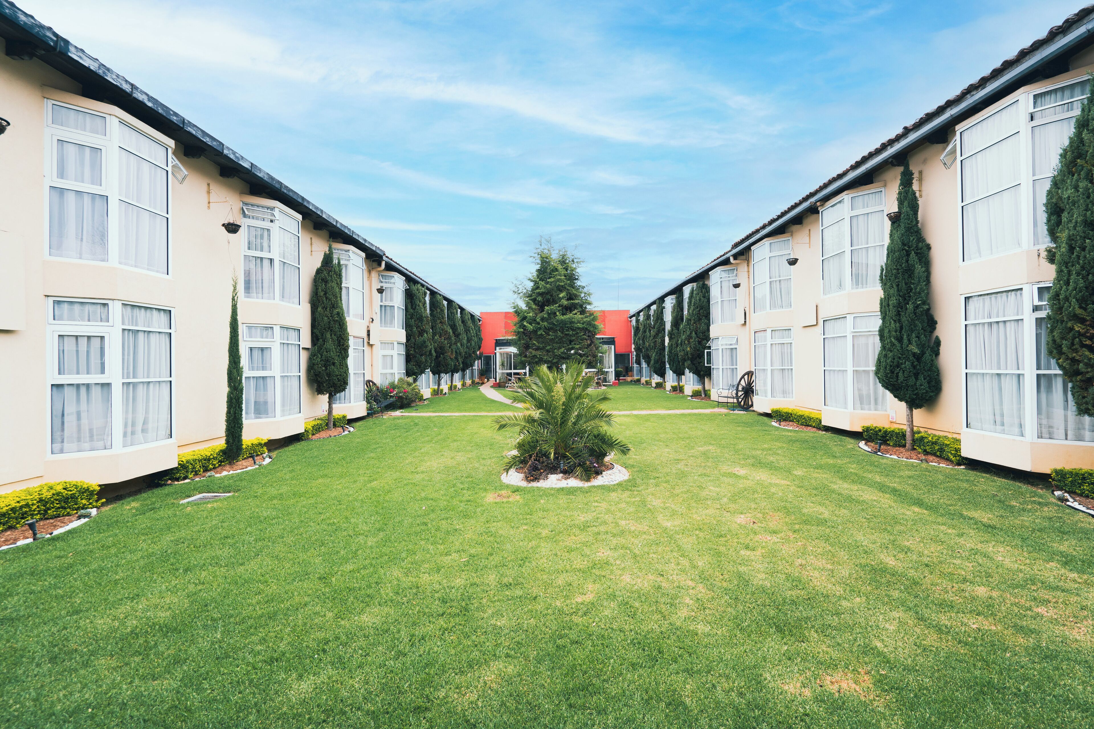 A row of modern, two-story buildings with large windows and a central lawn area.