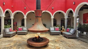 A spacious courtyard with a central fountain, multiple seating areas, and a vibrant red wall.