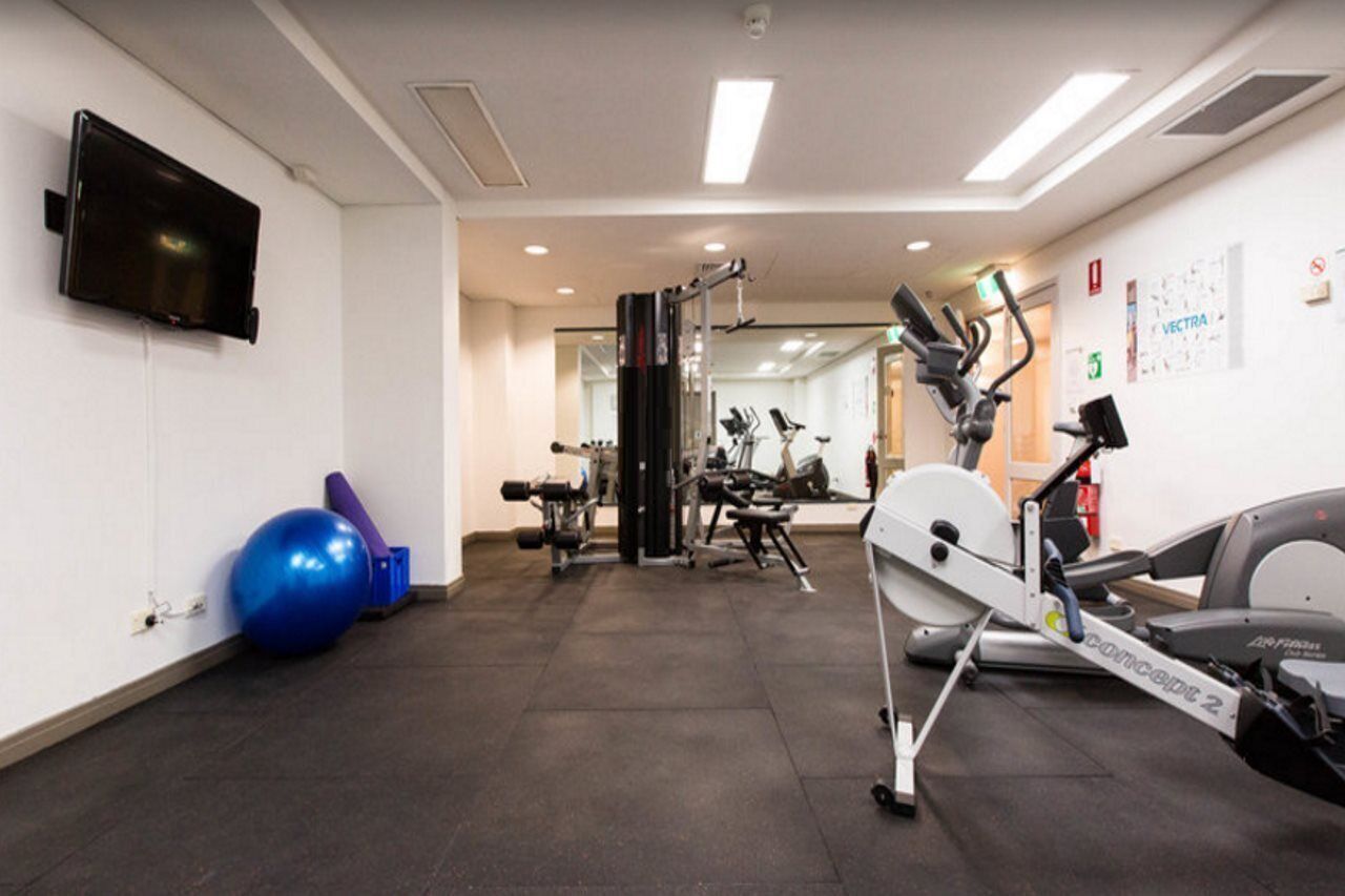 A gym with cardio machines, weightlifting equipment, and exercise balls.