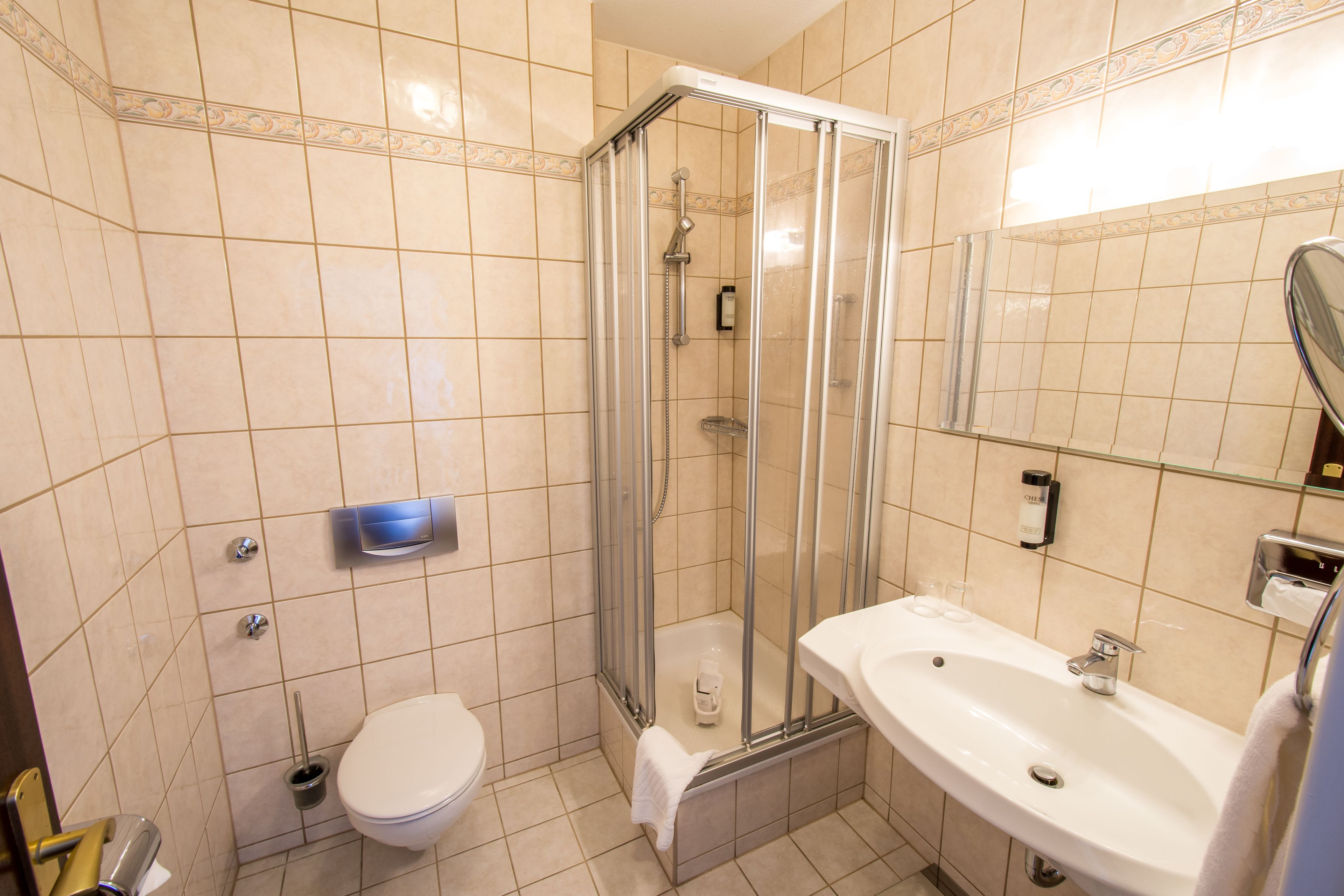 Une salle de bain avec une douche à parois de verre, un lavabo blanc et des toilettes.