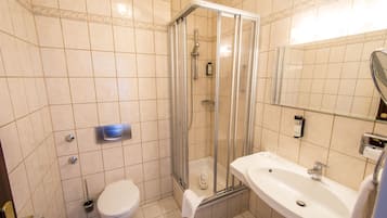 Une salle de bain avec une douche à parois de verre, un lavabo blanc et des toilettes.
